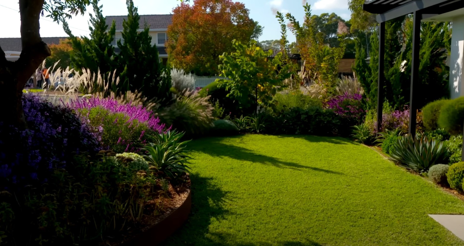 Beautiful curved lawn with vibrant flower borders and mature trees