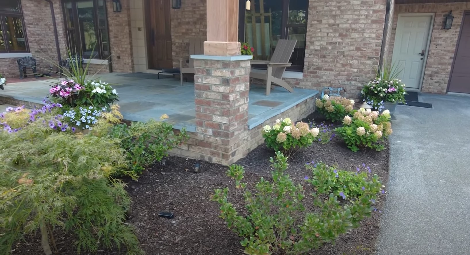 Elegant patio design featuring natural stone construction and seasonal plantings Custom outdoor patio with professional stone work and container plantings