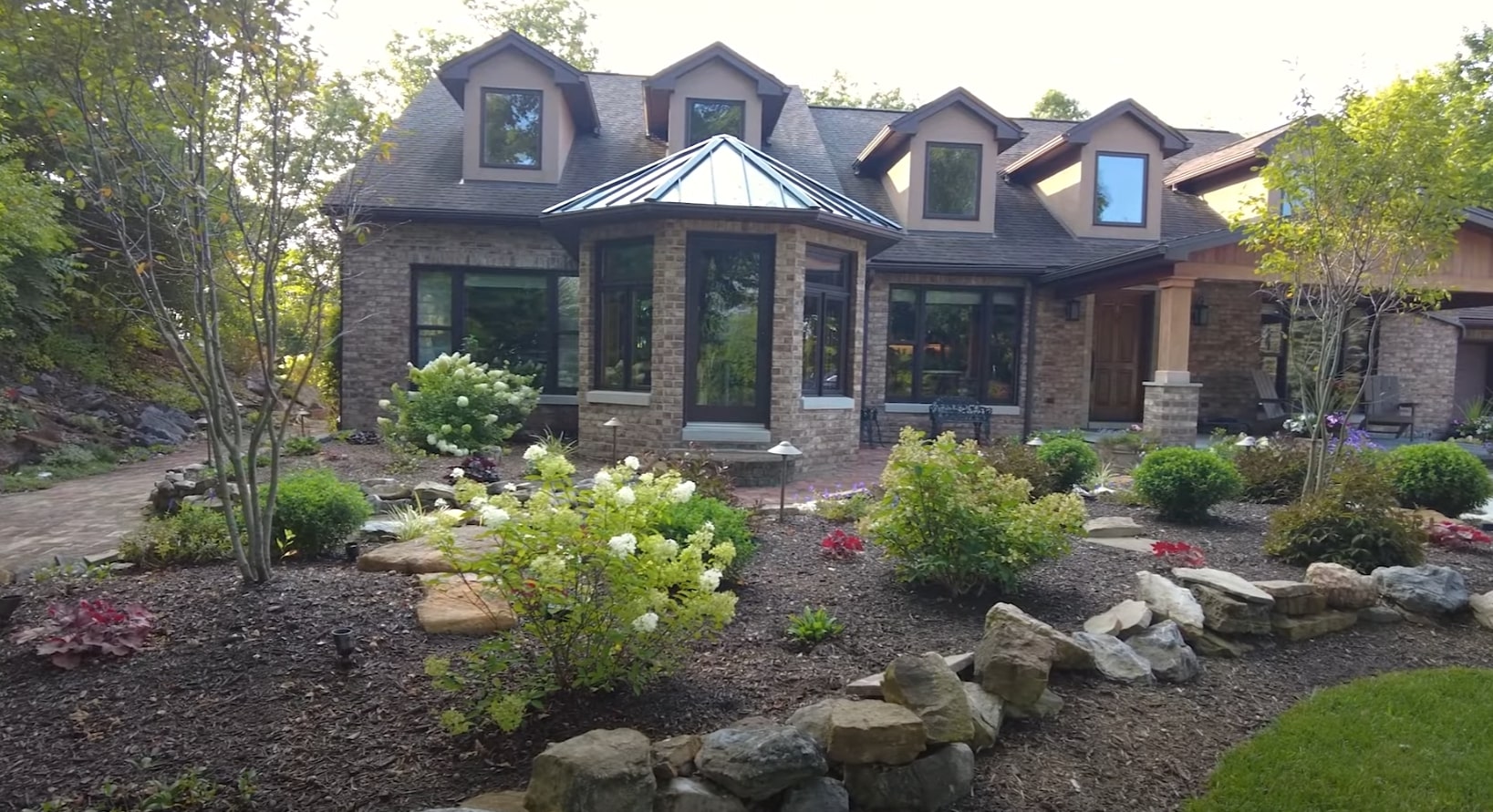 Professional landscaping design featuring natural stone elements and lush plantings Beautiful landscaped front yard with professional stone work and native plants
